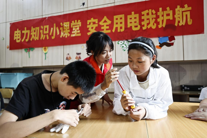 图：国网重庆市南供电公司红岩共产党员服务队队员在为孩子们讲解日常使用的工器具（龚超摄）