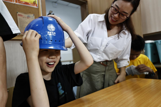 图：重庆市特教中心的孩子试戴安全帽（龚超摄）