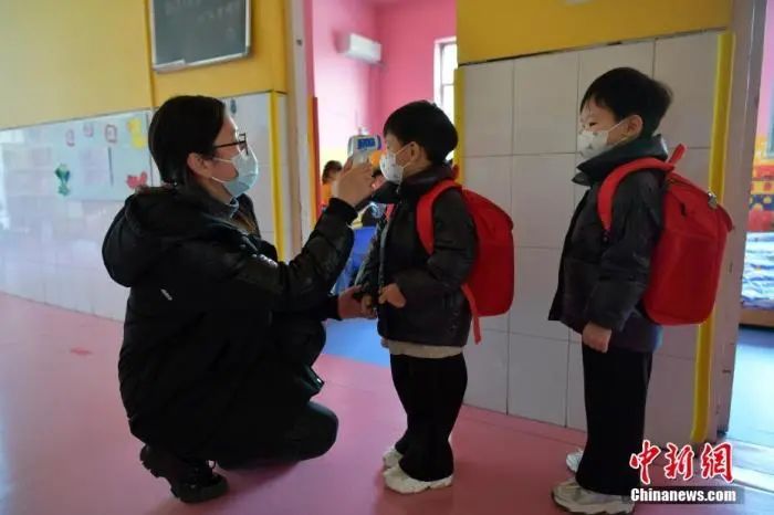 资料图：河北石家庄市某幼儿园，老师为小朋友测量体温。中新社记者 翟羽佳 摄