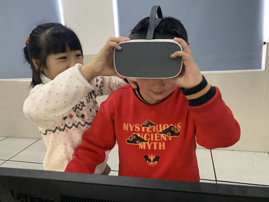 合肥市小学生正在用VR头盔体验自己用XRmaker图形编程软件创作的场景内容。