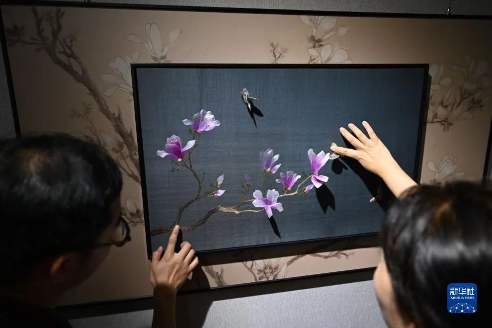 在北京景山公园举办的锦绣中华·紫禁之巅——传统织染绣艺术与生活展上，观众与展出的苏绣互动。新华社记者 金良快 摄