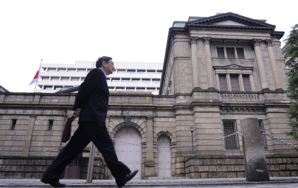 图说： 一名行人从位于日本东京的日本央行总部前走过（2013年3月4日摄）。 新华社发（关贤一郎摄）