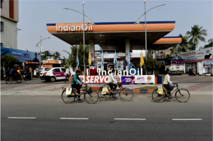 ▲印度街头，几个年轻人骑车驶过一处加油站。图/IC photo