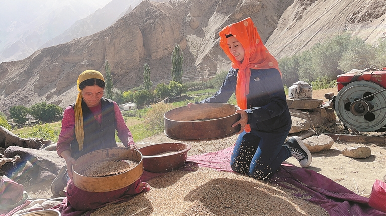 谭婉静（右）与塔什库尔干塔吉克自治县村民一起筛谷粒（资料图片）。