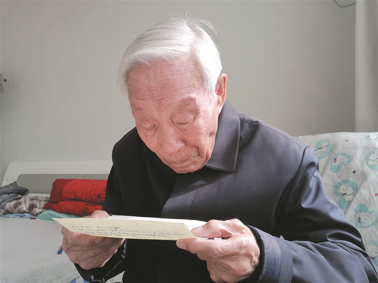 王鑫老人阅读战友的来信（资料图片）。张新慧 提供