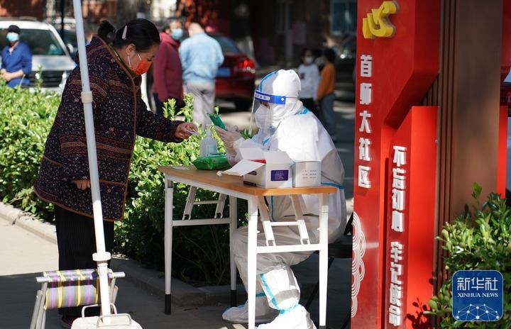↑5月13日，在北京市海淀区八里庄街道首师大社区的一处临时核酸检测采样点，工作人员登记市民信息。新华社记者 任超 摄