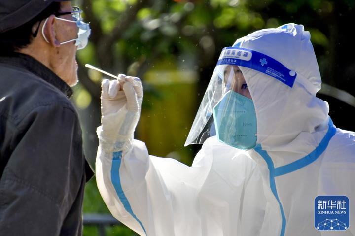 ↑5月13日，一名医护人员在朝阳区八里庄街道朝阳无限社区的检测点为居民做核酸检测。新华社记者 李欣 摄