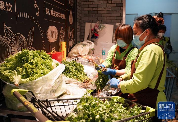 ↑5月13日，在位于北京市海淀区的超市发双榆树店，工作人员包装蔬菜。新华社记者 任超 摄