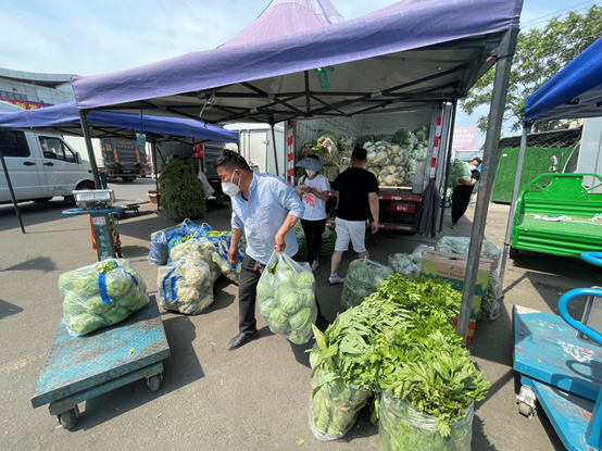 △新发地市场蔬菜1区，商户张先生（左）的摊位上摆满了新鲜蔬菜