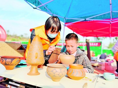在位于河南省的仰韶村国家考古遗址公园里，孩子们在志愿者的辅导下绘制彩陶。光明日报记者 李韵摄/光明图片