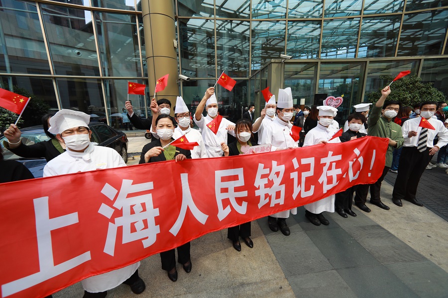 5月27日，在上海市黄浦区一家酒店，工作人员挥舞国旗欢送福建省援沪医疗队。 中国日报记者 朱兴鑫 摄