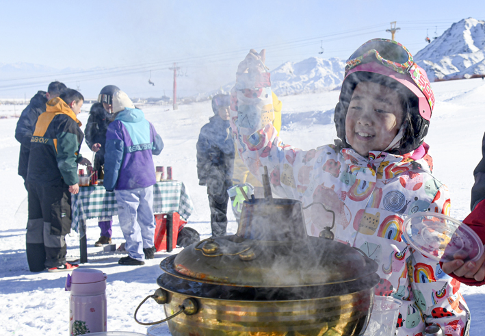新疆白云国际滑雪场，小朋友在雪场举办的冰雪火锅节上等待品尝美食 新华社图