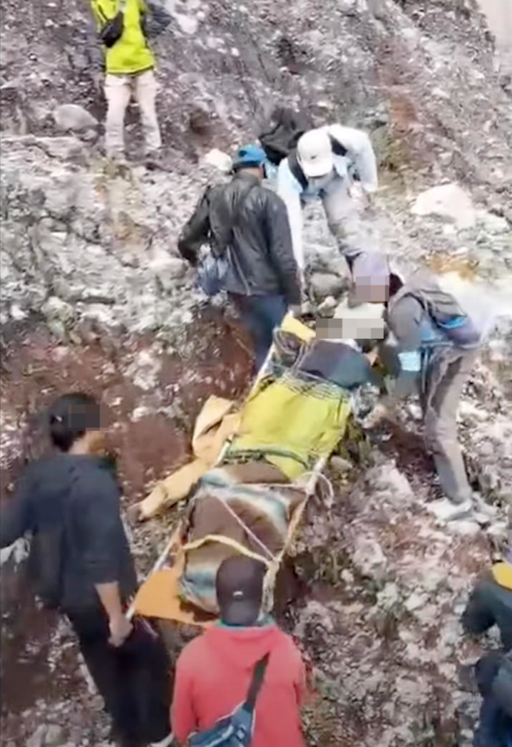 ▲救援人员将遗体从悬崖下运出